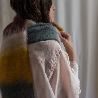 Foto de mujer de espalda luciendo un foulard de mohair, suave, cálido y ligero. Está hecho a mano por los artesanos riojanos de Ezcaray. Real Fábrica.