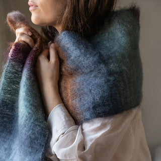 Mujer envuelta en un foulard de mohair en 3 colores: rosa, azul y berenjena. El tejido artesano es de gran calidad, suave y muy cálido. Real Fábrica.