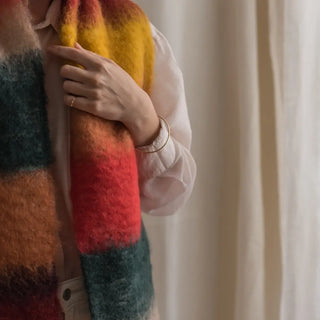Una mujer toca con su mano el foulard de mohair de franjas verdes que lleva al cuello, una fibra suave y de gran calidad desarrollada por Ezcaray, en la Rioja. Real Fábrica.