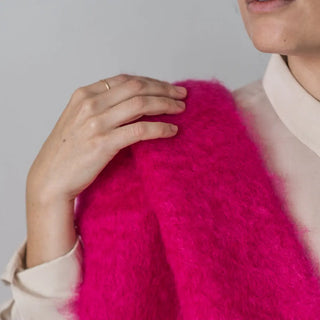 Mujer posa sobre su hombro un foulard de mohair de color fucsia. Está confeccionado a mano por los artesanos de Ezcaray, en La Rioja. Real Fábrica.