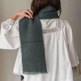 Foto de mujer de espalda con un foulard de mohair color gris marengo en su hombro, tejido a mano por los artesanos de Ezcaray. Real Fábrica.