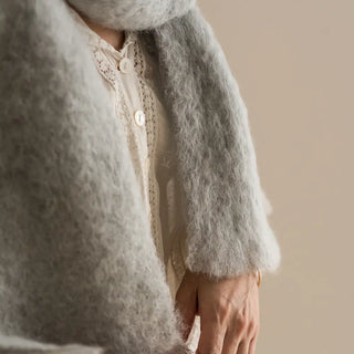 Mujer con un foulard de mohair de color gris perla, tejido a mano por los artesanos de Ezcaray. Real Fábrica.