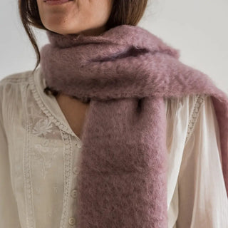 Foto de mujer luciendo un foulard de mohair hecho con lana riojana de color lila de Real Fábrica. 