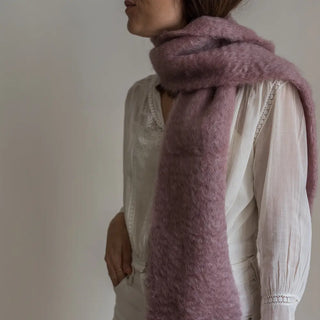 Foto de mujer de perfil luciendo en su cuello un foulard con una fibra suave y de gran calidad desarrollada por Ezcaray, en la Rioja. Real Fábrica.