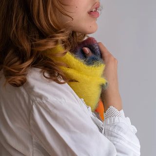 Mano de mujer tocando un suave foulard de mohair con diseño de franjas. El mohair es suave y abrigado, perfecto para regalar en invierno. Real Fábrica.