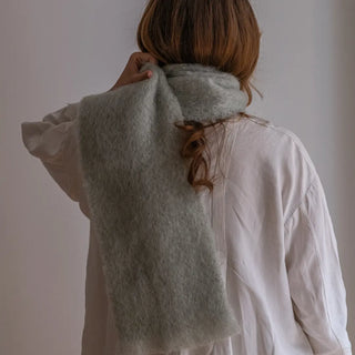 Mujer vista de espaldas y abrigada con un foulard de mohair verde claro, de gran calidad. Está confeccionado por las manos expertas de los artesanos de Ezcaray. Real Fábrica.