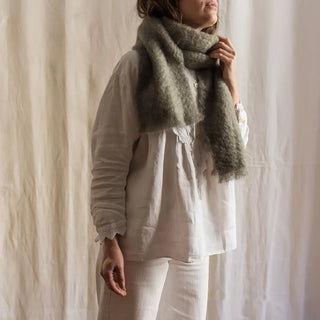 Foto de mujer de perfil luciendo una bufanda de mohair, suave, cálida y ligera. Está hecho a mano por los artesanos riojanos de Ezcaray. Real Fábrica.