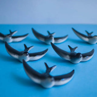 Foto mostrando en un plano azul una bandada de 6 golondrinas de cerámica de Valencia. Real Fábrica.