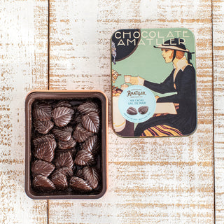 Imagen lata estilo Art Decó hojas de cacao 70€ flor de sal. Lata abierta con las hojas de chocolate dentro.