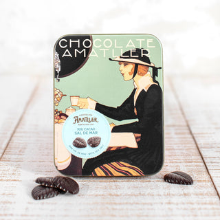 Imagen lata estilo Art Decó hojas de cacao 70€ flor de sal. Lata cerrada con hojas de chocolate en la mesa.