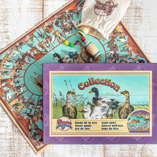 Plano cenital de la caja de cartón del juego de la oca con ilustraciones antiguas, en horizontal sobre una mesa de madera blanca. Debajo, el tablero abierto en posición oblicua con las fichas del juego. Real Fábrica.