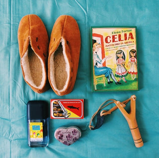 Libro Celia Institutriz en América. Fotografía libro junto a babutxes, caramelos de violeta y tirachinas. Real Fábrica