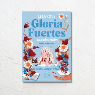 Portada ilustrada de “El libro de Gloria Fuertes para niñas y niños”. Fondo azul con flores, libros abiertos y una ilustración de Gloria Fuertes acompañada de un gato y una taza. Subtítulo: Versos, cuentos y vida. Ilustrado por Marta Altés.