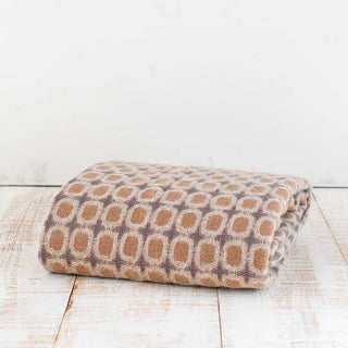 La manta riojana, elaborada a mano con una mezcla de mohair y lana, destaca por su intrincado diseño de círculos, lo que demuestra un trabajo minucioso en cada detalle y una textura suave que proporciona calidez sin exceso de peso. Real Fábrica.