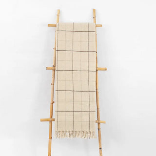 Manta maragata líneas marrón expuesta sobre una escalera de madera vintage. La lana es 100% pura de oveja, y con los procesos de fabricación se consigue un tejido ligero y que conserva el calor. Real Fábrica. 