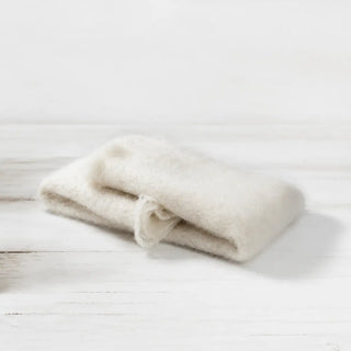 Detalle de manta de mohair en color blanco, con terminación en flecos finos. En el primer plano se aprecia la textura de la fibra de mohair. Real Fábrica.