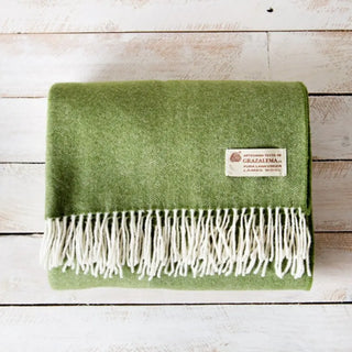 Manta de lana merino con un dibujo de espiga en color verde. Está confeccionada  a mano en Grazalema, Cádiz. Real Fábrica.