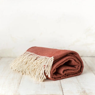 Manta de lana merino con un dibujo de espiga en color teja. Está confeccionada  a mano en Grazalema, Cádiz. Real Fábrica.