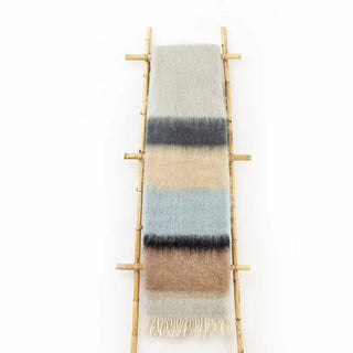 Manta mohair de rayas azul, negro y verde, con flecos colgada sobre una escalera de madera vintage. Real Fábrica