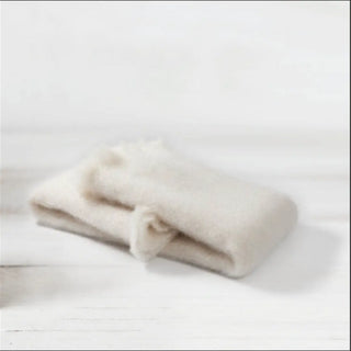 Detalle de manta de mohair en color blanco, con terminación en flecos finos. En el primer plano se aprecia la textura de la fibra de mohair. Real Fábrica.