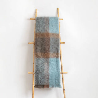 Manta mohair de ezcaray cuadros azul y marrón colgada de una escalera vintage. Real Fábrica.