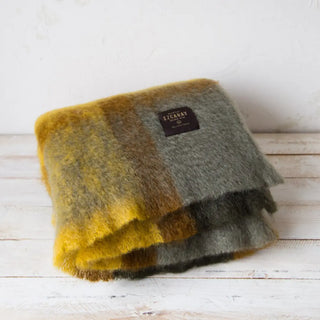 Manta de mohair de cuadros verde y mostaza. Está hecho a mano por los artesanos riojanos de Ezcaray. Real Fábrica. Real Fábrica.