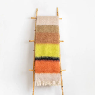 Manta mohair de ezcaray de rayas amarilla negro y marrón colgada de una escalera vintage. Real Fábrica.