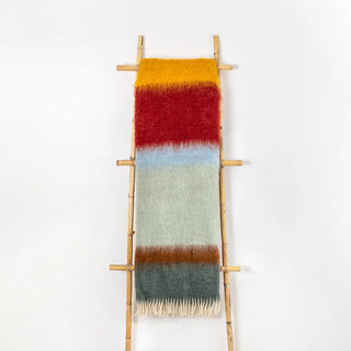 Manta mohair de rayas burdeos y verde, con flecos colgada sobre una escalera de madera vintage. Real Fábrica