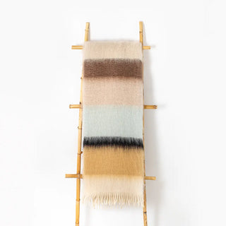 Manta mohair de ezcaray de rayas marrón, mostaza, marengo colgada de una escalera vintage. Real Fábrica.