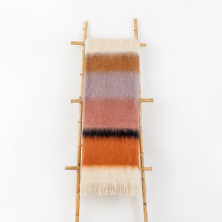 Manta mohair de ezcaray de rayas rosa, naranja y lila colgada de una escalera vintage. Real Fábrica.