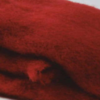 Detalle de manta de mohair en color rojo oscuro, con terminación en flecos finos. En el primer plano se aprecia la textura de la fibra de mohair. Real Fábrica.
