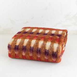 Esta elegante manta de mohair, que aparece en la imagen, se destaca por su brillo natural y una suavidad única, fabricada en Ezcaray siguiendo técnicas tradicionales. Real Fábrica.