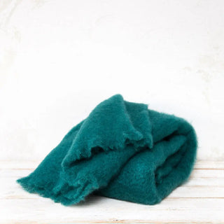 Manta de mohair color verde esmeralda. En el primer plano se aprecia la textura de la fibra de mohair. Real Fábrica.