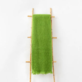 Manta mohair de ezcaray en color verde primavera colgada de una escalera vintage. Real Fábrica.