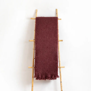 Manta de mohair de color vino tinto colgada en una escalera vintage. Real Fábrica