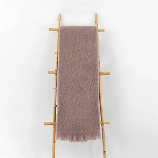 Manta de mohair de confección artesana en color visón terminación en flecos a tono expuesta sobre una escalera vintage. Real Fábrica.