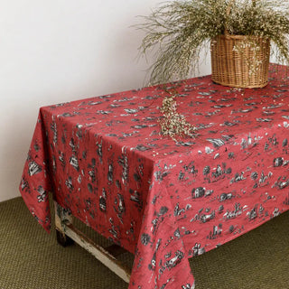 Mesa puesta con el mantel de la colección Quijote en color rojo con un cestro de mesa con flores. Real Fábrica