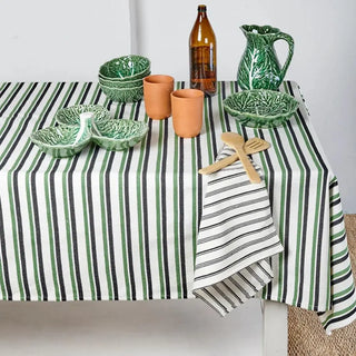 Mantel de rayas verdes, blancas y negras con vajilla de cerámica verde estilo vegetal, ideal para una mesa fresca y natural. Real Fábrica.