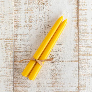 Foto cenital  de un pack de velas de cera de abeja hechas a mano formato estelas, sobre una mesa rústica blanca. Real Fábrica