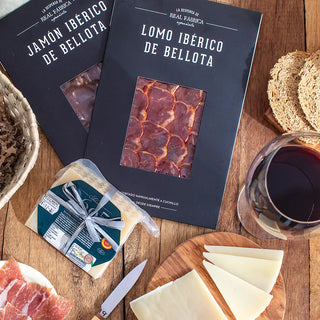 Plano cenital de los productos del pack Jamón, Lomo, Queso y Vino  sobre una mesa de madera. Real Fábrica