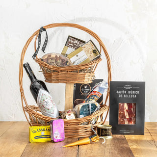 Pack gourmet hecho con productos españoles empaquetado en una cesta de dos pisos. Real Fábrica