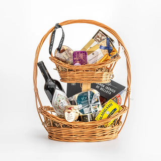 Pack con productos gourmet presentado en una cesta navideña de dos pisos. Real Fábrica