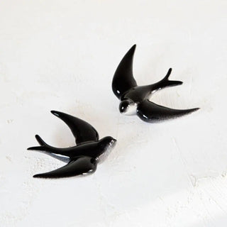 Foto mostrando las dos golondrinas de cerámica de color negro, estilizadas y con larga cola. Real Fábrica.