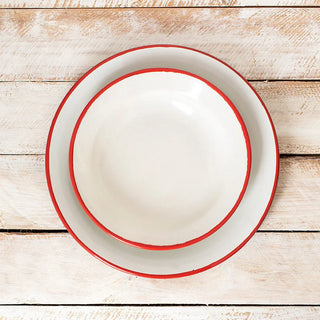 Plato hondo de peltre blanco con filo rojo junto a plato llano