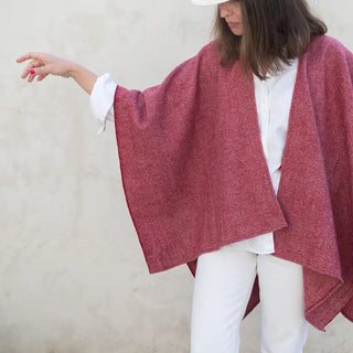Foto de mujer mostrado de una manera elegante nuestra capa de lana merino de Grazalema en color burdeos. Real Fábrica