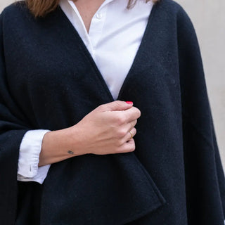 Foto de mujer mostrando nuestra Capa ponchito de lana merino color negro. Real Fábrica