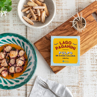 Una mesa de aperitivo con una tapa de conserva de pulpo en ajada gallega de gran calidad, acompañada de picos artesanos. Real Fábrica.