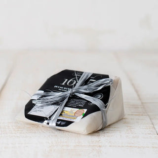 Foto de queso manchego semicurado DOP, se puede apreciar su presentación tradicional adornada con un lazo atado al queso. Real Fábrica.