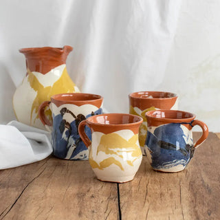 Bodegon con diferentes piezas de cerámica del mismo estilo entre los que se encuentra una taza azul y blanca. Real Fábrica