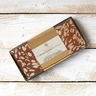 Foto cenital de un turrón de chocolate y almendras, sobre una mesa de madera. Real Fábrica.